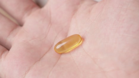 Hand-Zeigt-Der-Kamera-Eine-Omega-3-Fischölkapsel