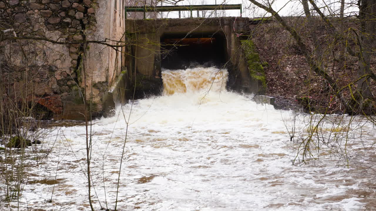 Water flowing from sluice on the river, focus pull