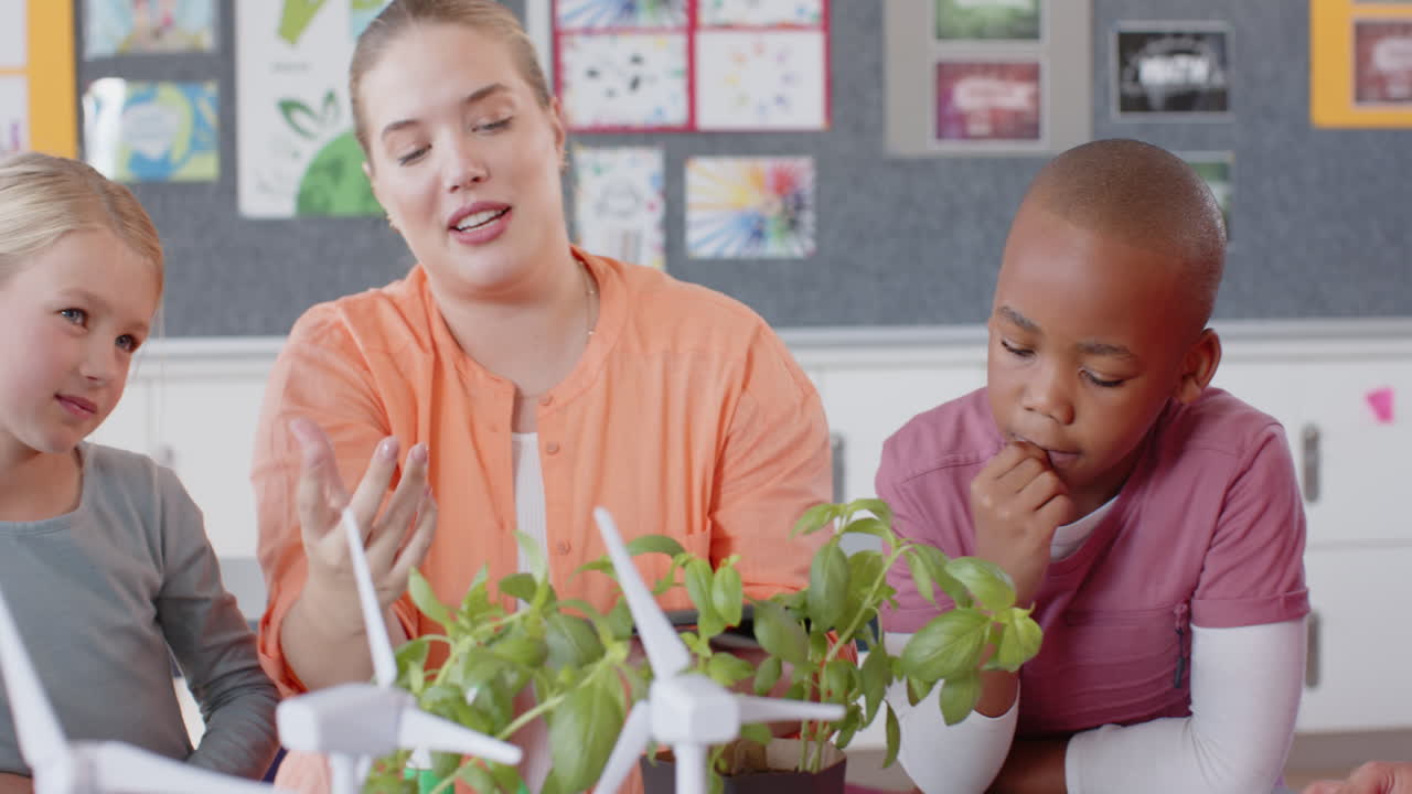 In school, female teacher and students discussing plants and wind turbines in classroom