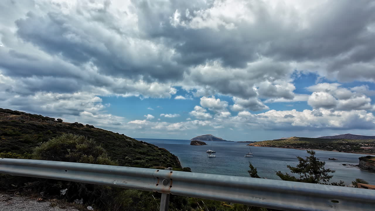 conducción en cámara lenta en una calle con vistas al mar y colinas verdes, cielo nublado y copia espacio en grecia