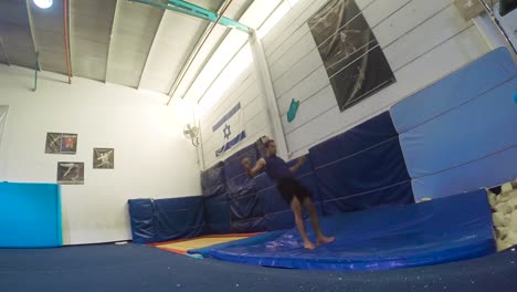 a slow motion still shot of a guy doing flips from the trampoline landing and winning having fun and working out in 60fps