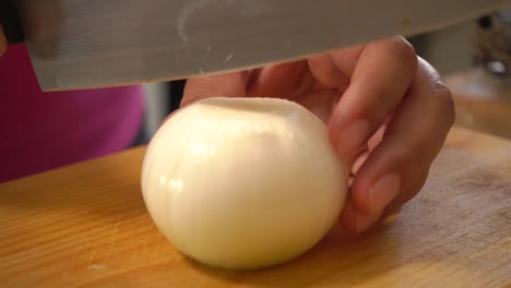 a white onion cut in half then sliced on a cutting board