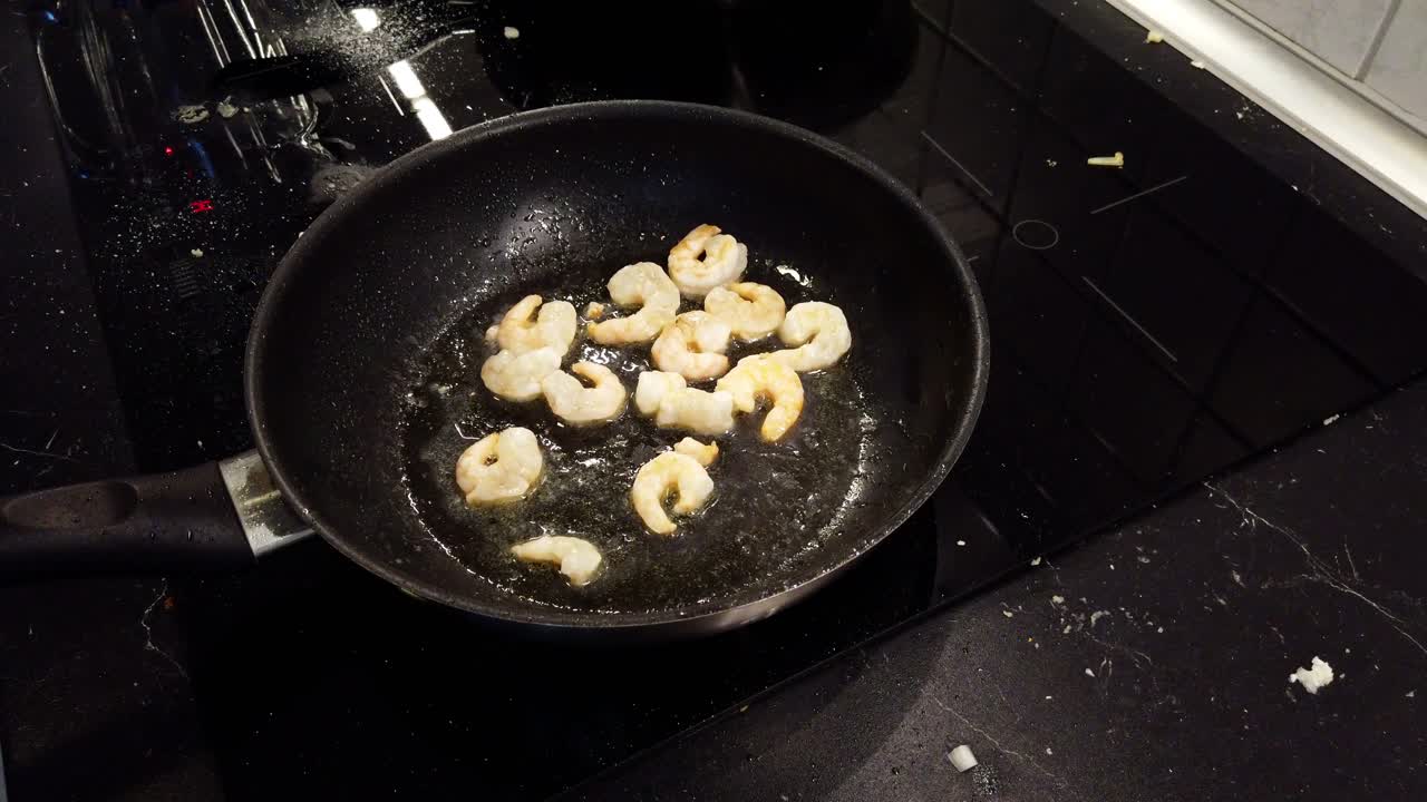Frying a few shrimps in a black pan