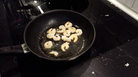 frying a few shrimps in a black pan