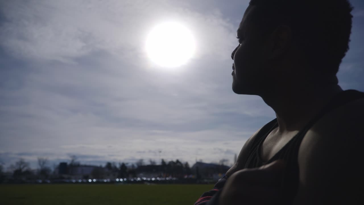 자신을 교차하는 남성 앉아 - 4k에서 강력한 운동 근육질의 흑인 남성 피트니스 야외 훈련 준비