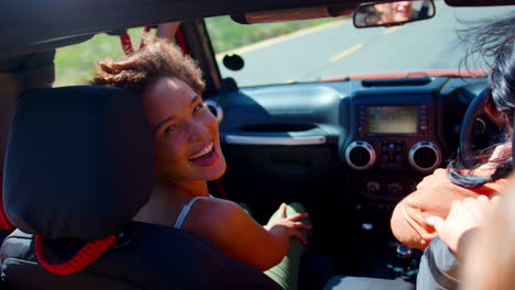 retrato de amigas riendo divirtiéndose en un coche de techo abierto en un viaje por carretera