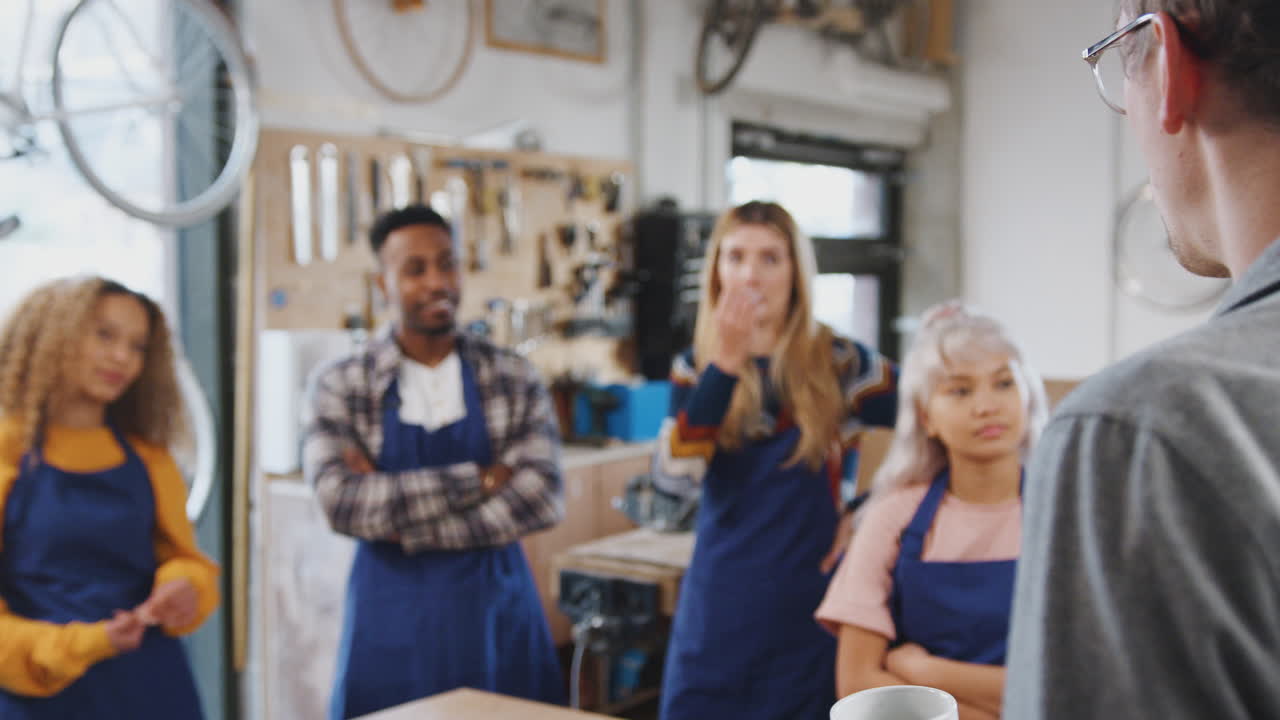Multi-Cultural Team Of Trainees In Workshop Learn How To Assemble Hand Built Bicycle Frame Together
