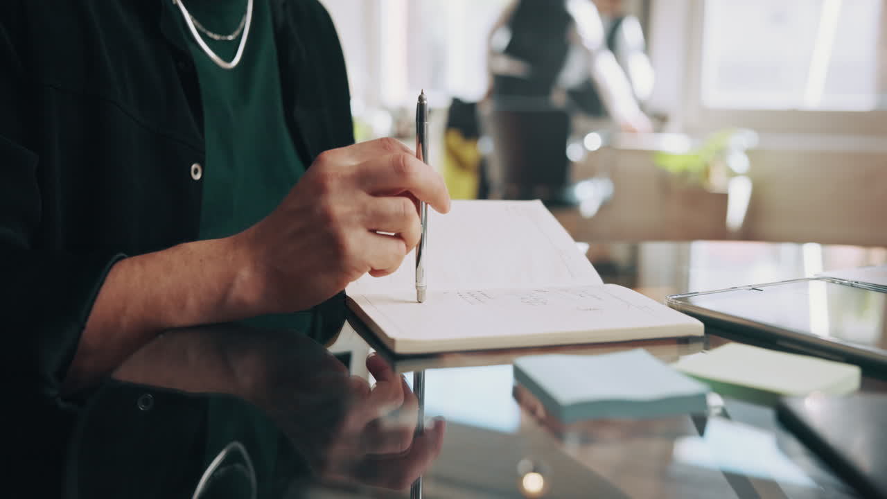 Close-Up of Person's Hand Writing Notes in a Notebook at an Office Desk