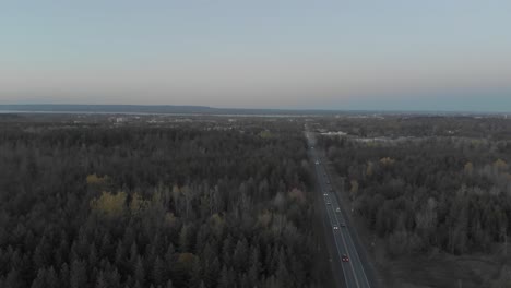 Luftaufnahmen,-Die-Sich-Nach-Rechts-über-Eine-Stark-Befahrene-Straße-Außerhalb-Von-Ottawa,-Ontario,-Bewegen,-Mit-Der-Skyline-Der-Stadt-In-Der-Ferne-Und-Einer-Blauen-Skyline