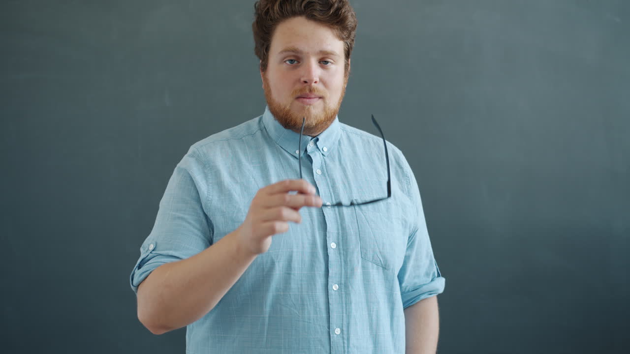 Uomo con una camicia azzurra che indossa occhiali da sole.
