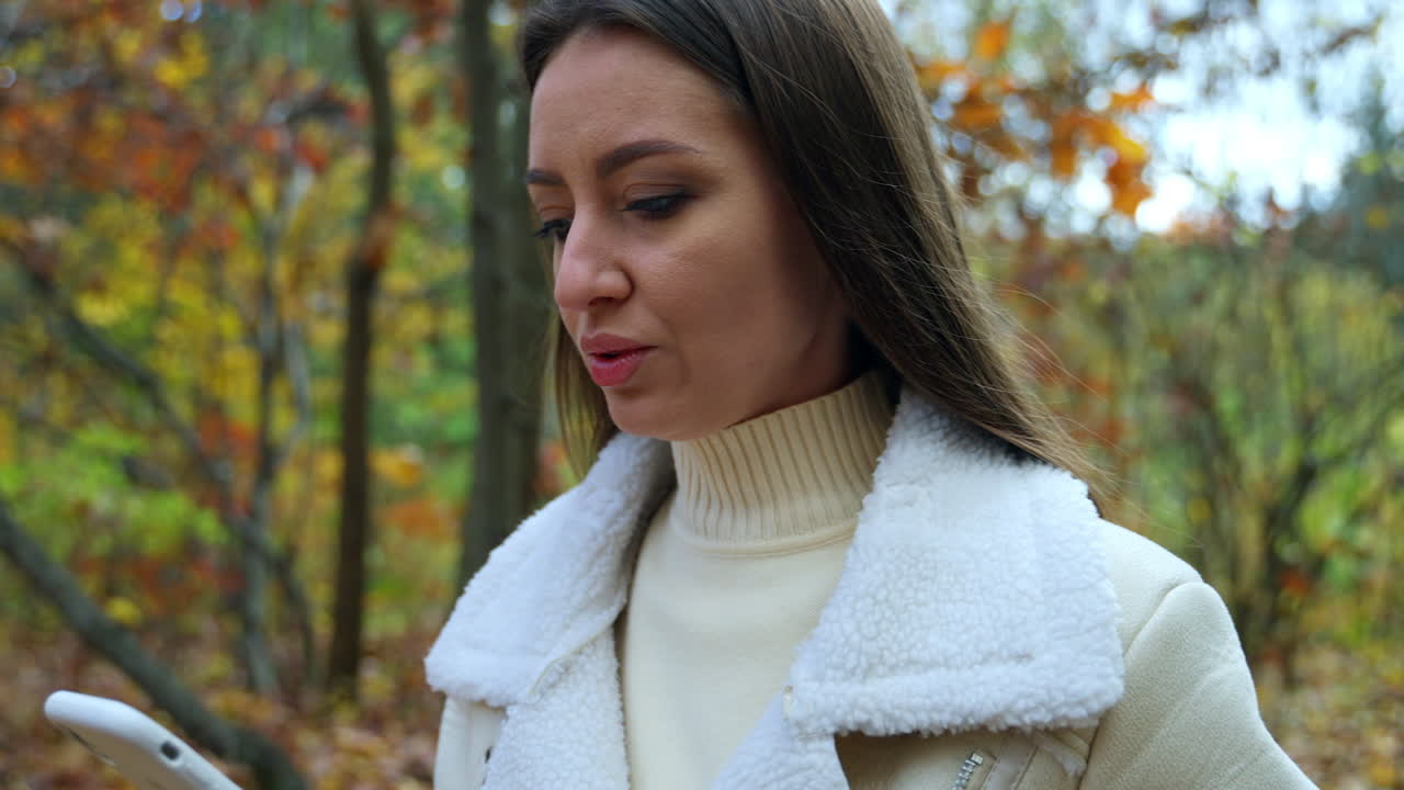 Woman in Autumn Park using Smartphone and Coffee