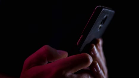 thumb scrolling on a smartphone close up in a dark room with red and white lighting