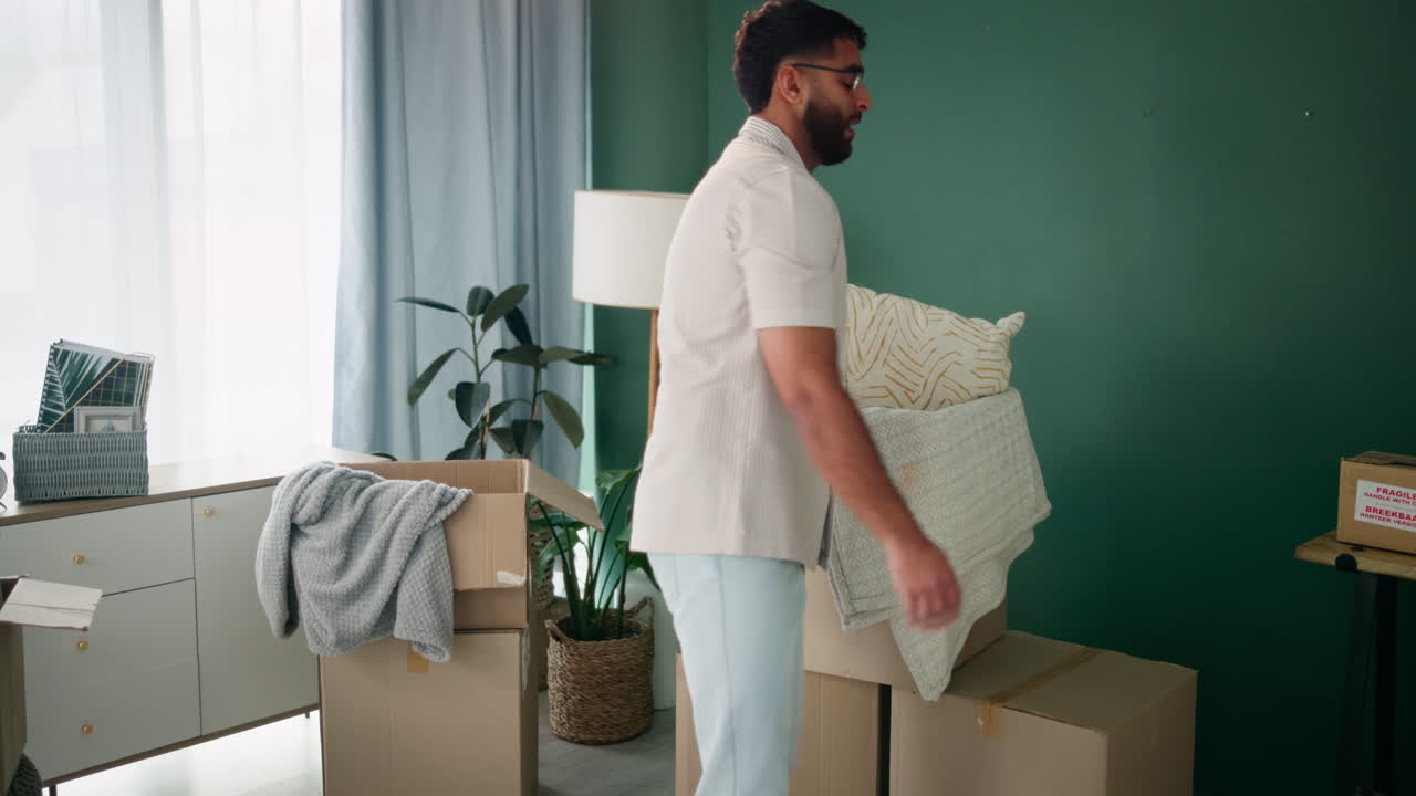 Man moving boxes and pillows in a new home