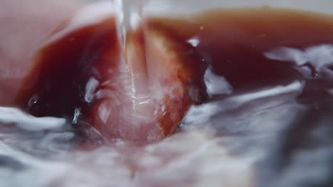 Macro-shot-of-a-water-stream-washing-a-dark-viscous-liquid-away