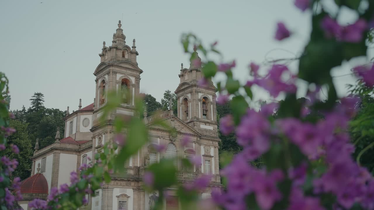 Fachada da igreja do Bom Jesus em Braga emoldurada por flores desfocadas