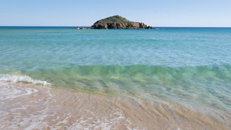 Clear-shallow-turquoise-water-with-little-rocky-island-in-the-horizon-in-South-Sardinia,-Italy