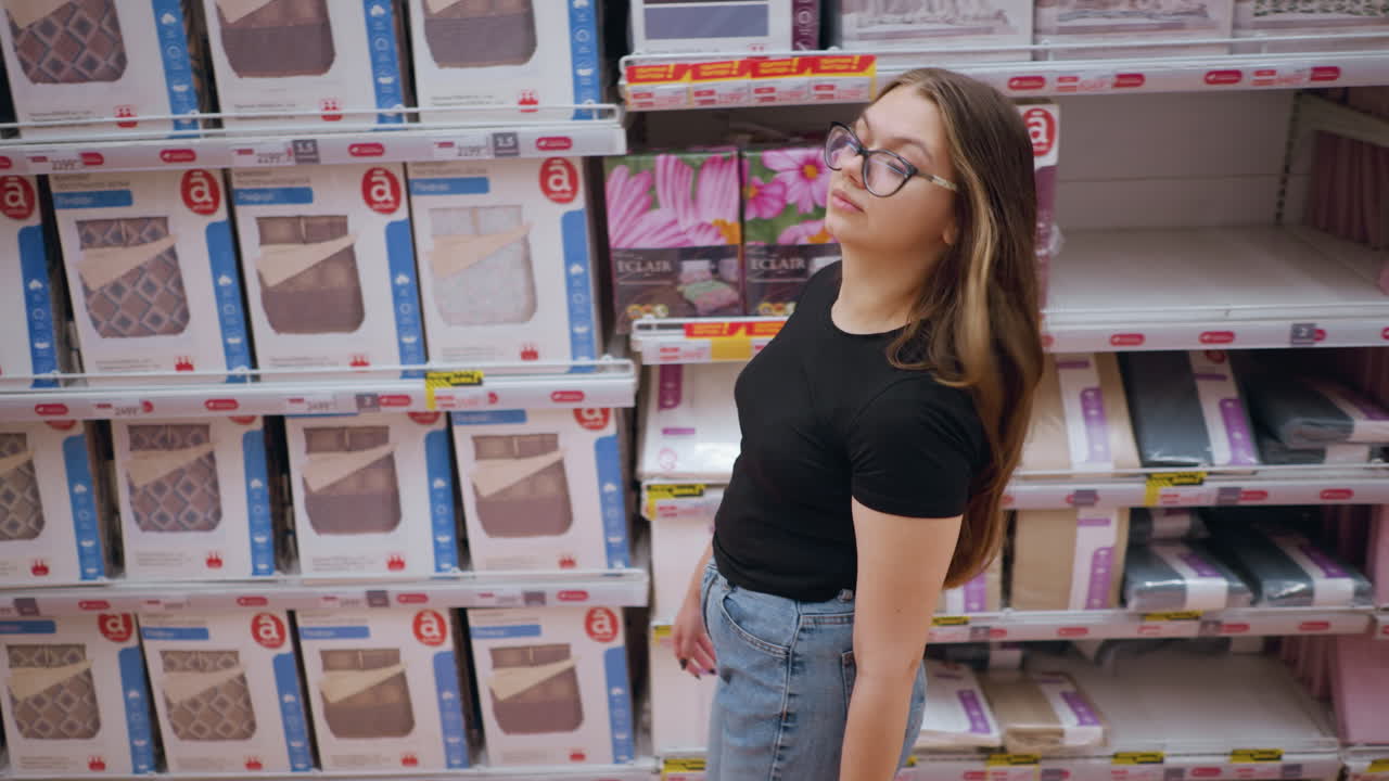 vista aérea de una mujer comprando en una tienda minorista, caminando por un estante lleno de productos de cama, ella mira a su alrededor mientras navega por las opciones disponibles, el pasillo de la tienda exhibe textiles para el hogar bien dispuestos