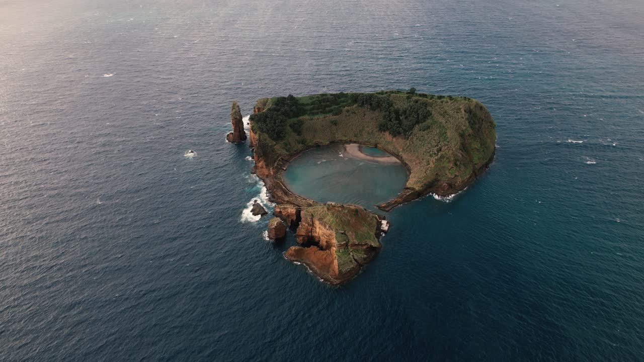 Aerial drone circling Ilheu de Vila Franca do Campo at an angle revealing volcanic cliffs and blue Atlantic waters around the island