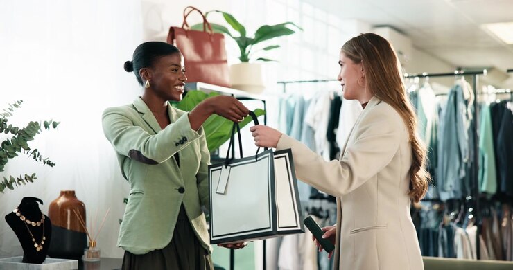 Shop Assistant Handing Shopping Bag to Customer in Boutique