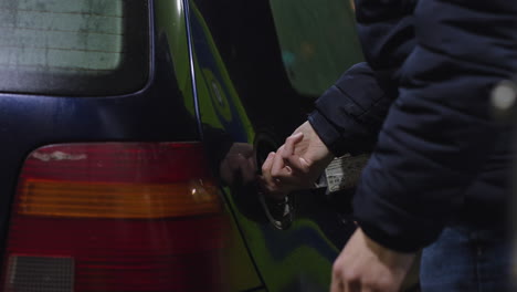 side view of man opening gas cover lid, unscrewing cap and placing on top of car, view from behind