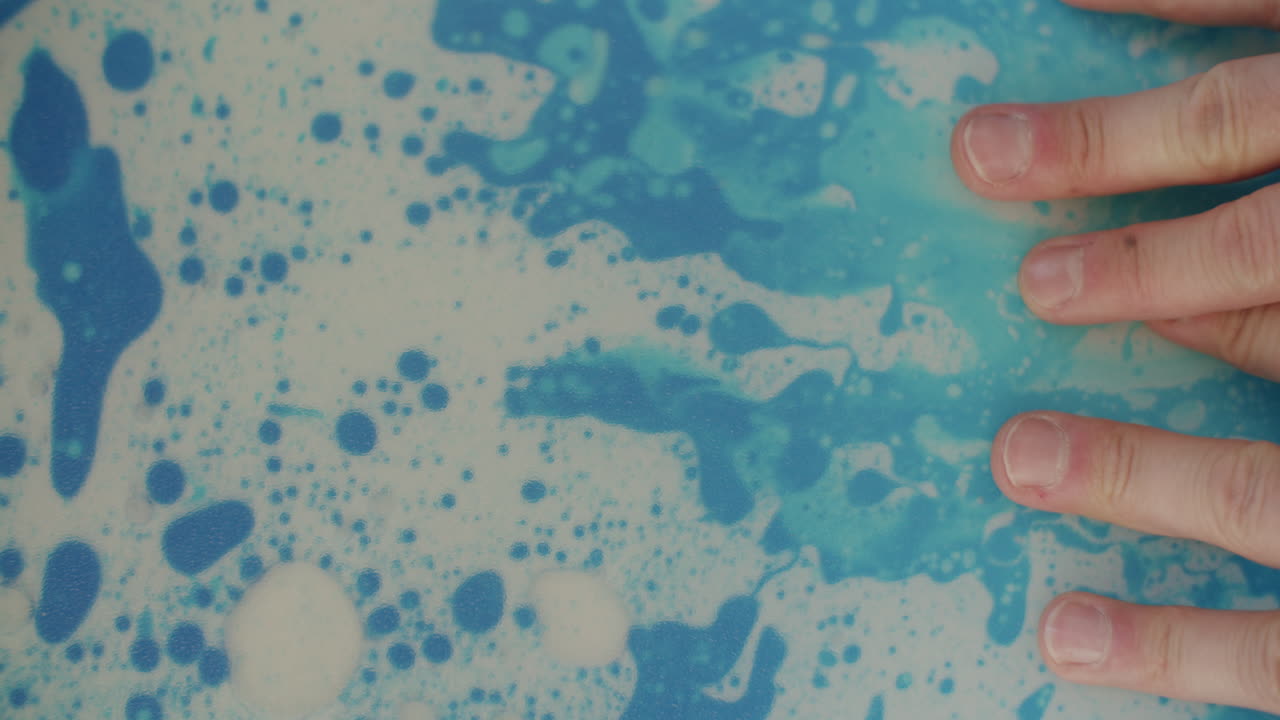 niño pequeño y adulto jugando con aceite, tinta y agua contenidos en un mate