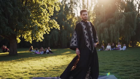 man dancing in a park with people sitting in the background