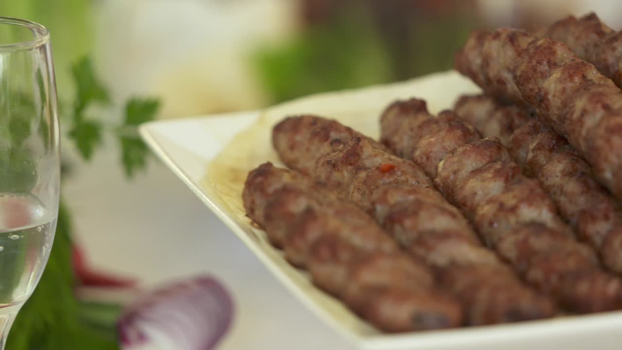 Doğranmış soğanla dekoratif bir tabakta servis edilen Ermeni lüle kebabı.