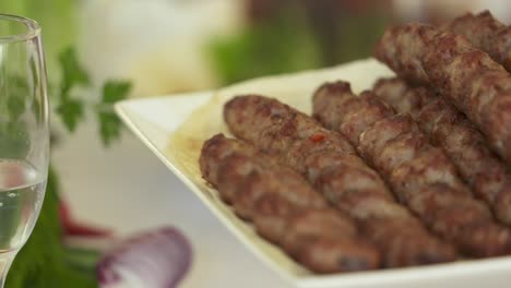 lula kebab armenio servido en una bandeja decorativa con cebolla picada