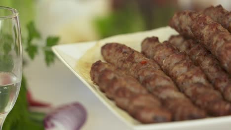 armenian lula kebab served on decorative platter with chopped onion