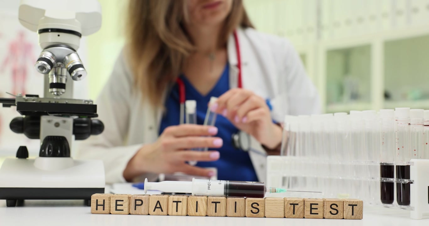 Parole 'test epatite' con microscopio e campioni di sangue
