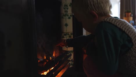 boy sitting near fireplace at home 4k