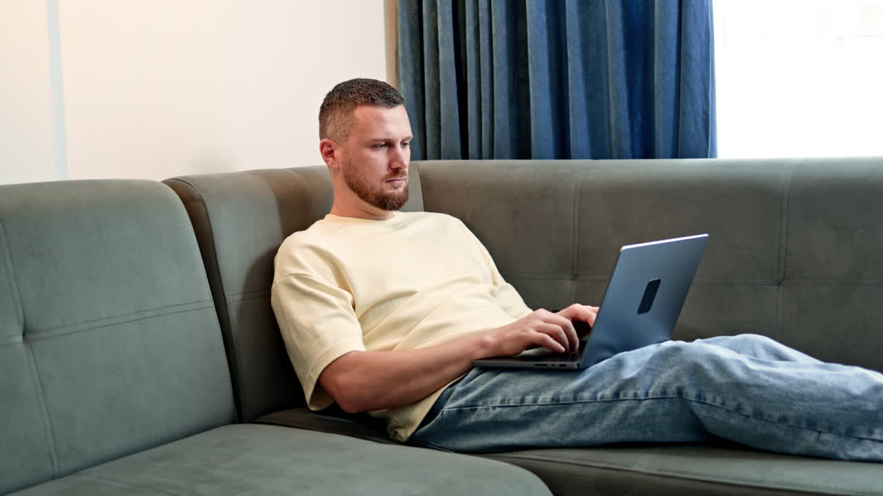 Mand arbejder på bærbar computer i stuen om dagen