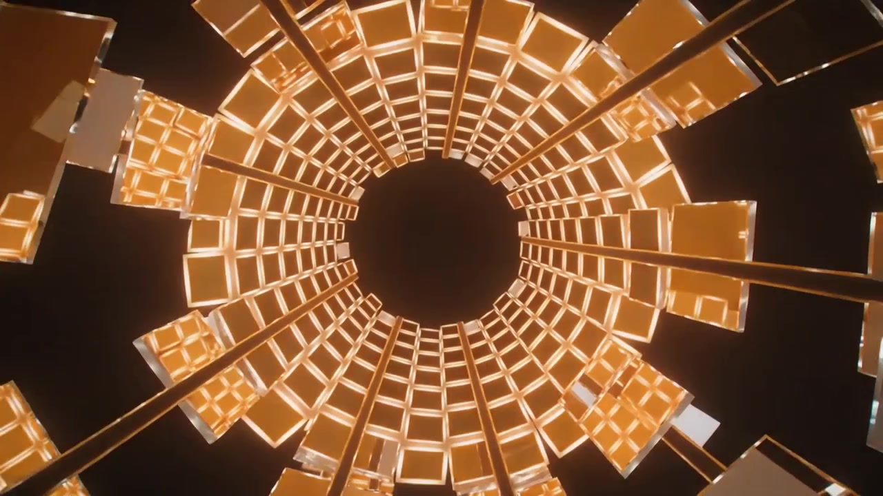 Cámara comenzando de arriba hacia abajo en un escenario oscuro, una celosía girando alrededor de un vacío, paneles creando un efecto de túnel