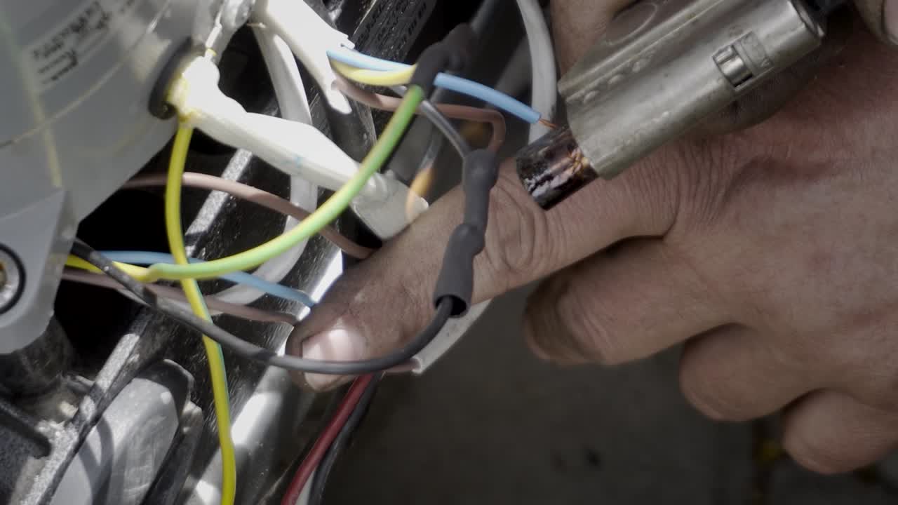 Soldering cambric on wires gas soldering iron, close-up.
