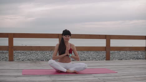 woman meditating on a beach pier