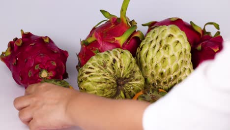 manos seleccionando frutas tropicales de una exhibición