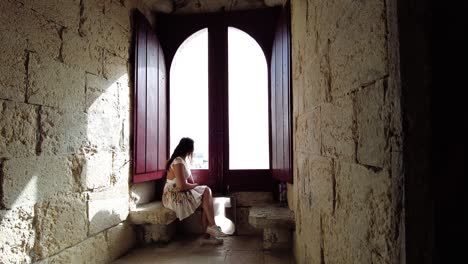 Touristin-Sitzt-Am-Großen-Holzfenster-Im-Belem-Turm-In-Lissabon,-Portugal