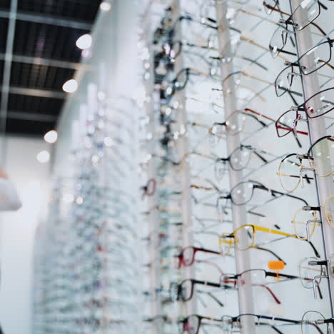 close-up glasses on the stand on the blur background with customer. fashionable eyeglasses in the optical store. vision concept.
