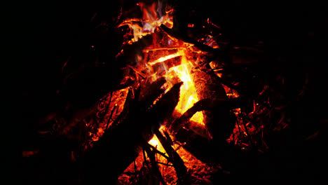 órbita-De-Paralaje-Alrededor-De-Una-Fogata-De-Madera-Que-Arde-En-Llamas-Rojas,-Violetas-Y-Azules-En-El-Viento