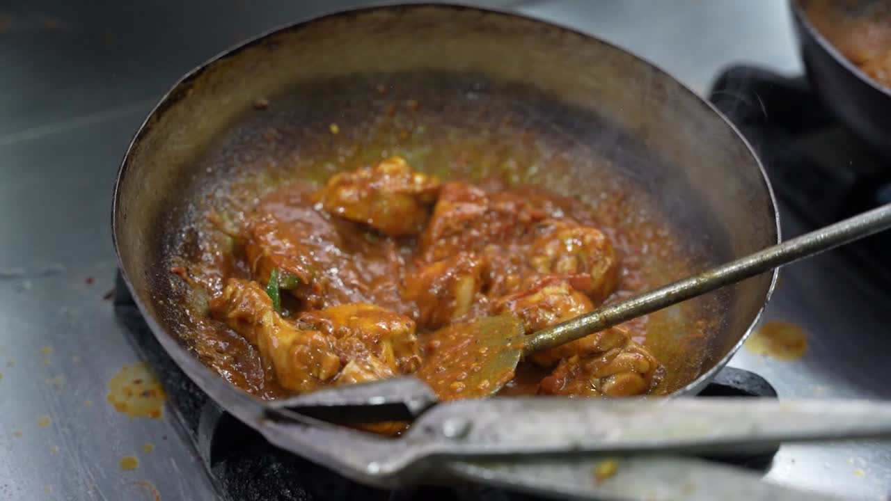 Spicy chicken karahi being prepared in a wok over flame in Pakistani eatery. Pakistan