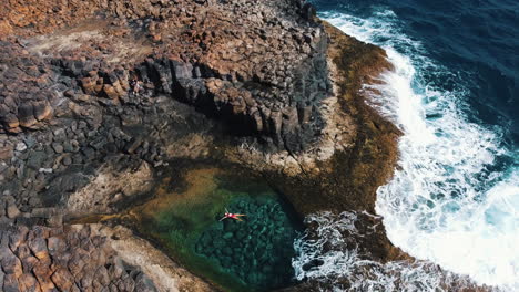 a woman is floating and enjoying the cove waters of caleta de fuste