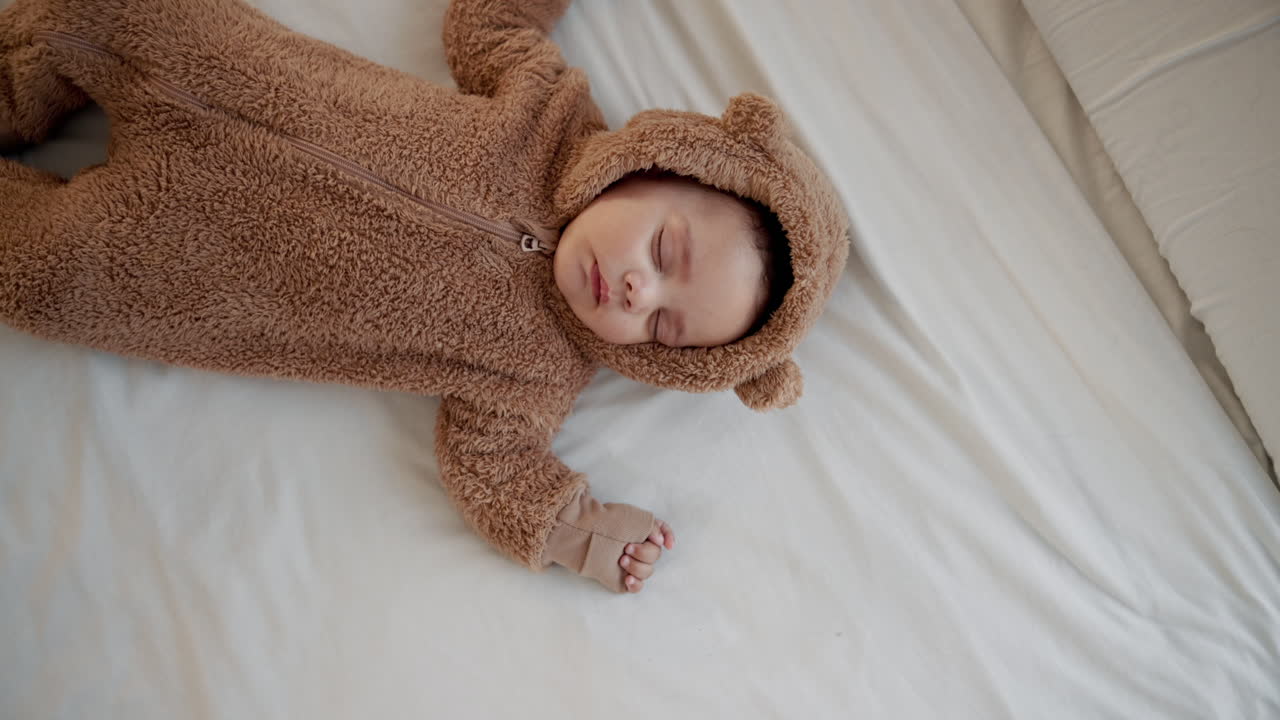 Bambino adorabile che dorme in una tutina da orso bruno.