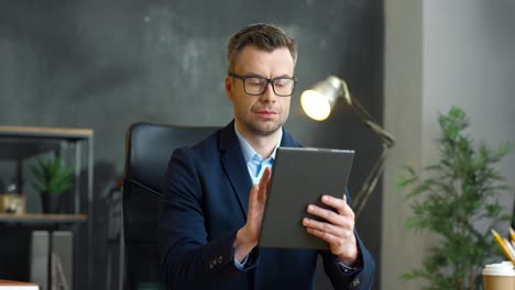 hombre de negocios con gafas usando tableta en la oficina