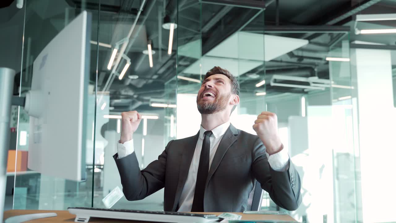 joven empresario guapo y alegre sentado en un escritorio, trabajando en una oficina moderna, arrojando dinero por encima de su cabeza