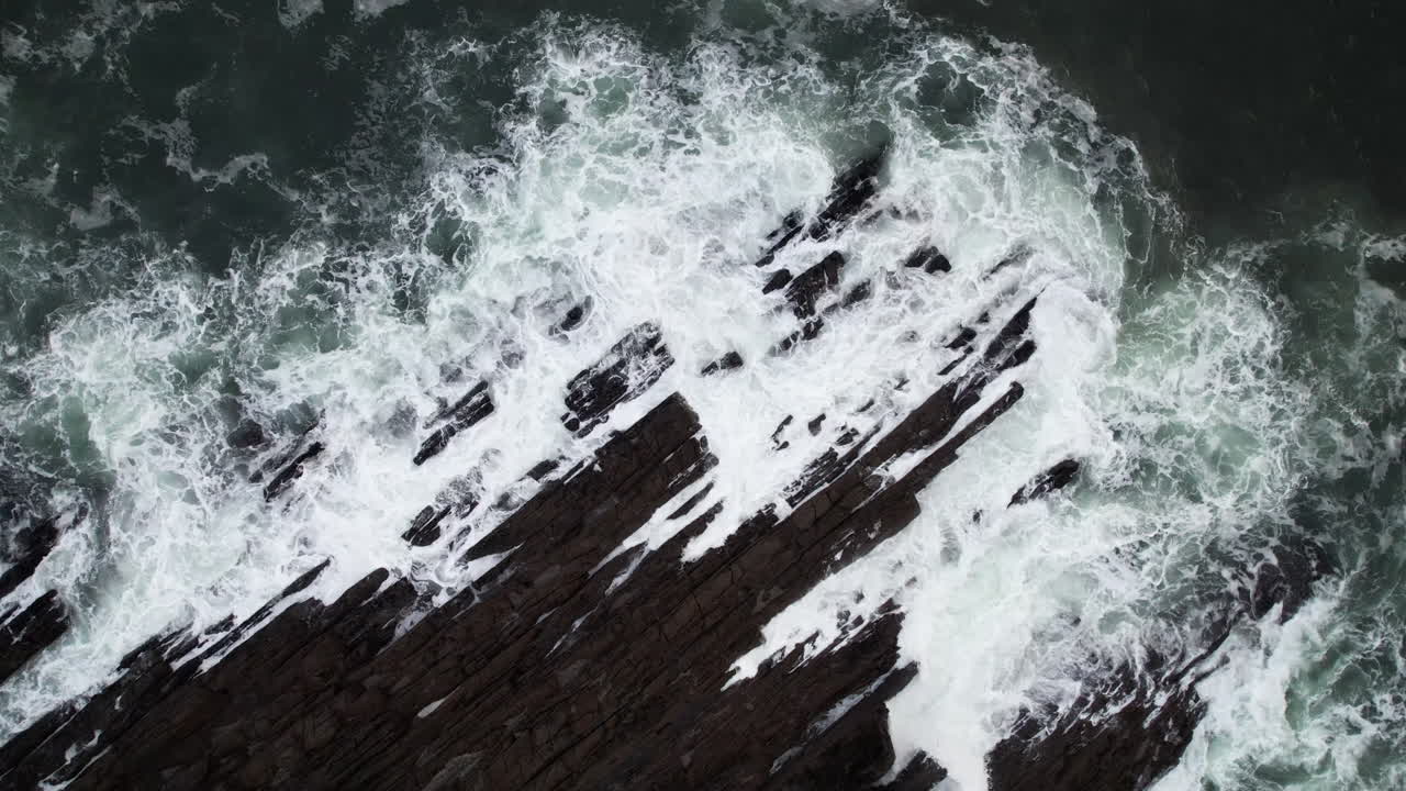 Birdseye Aerial View of Ocean Waves Crushing on Rugged Rocky Coastline on Cold Autumn Day in Ireland, Top Down Drone Shot