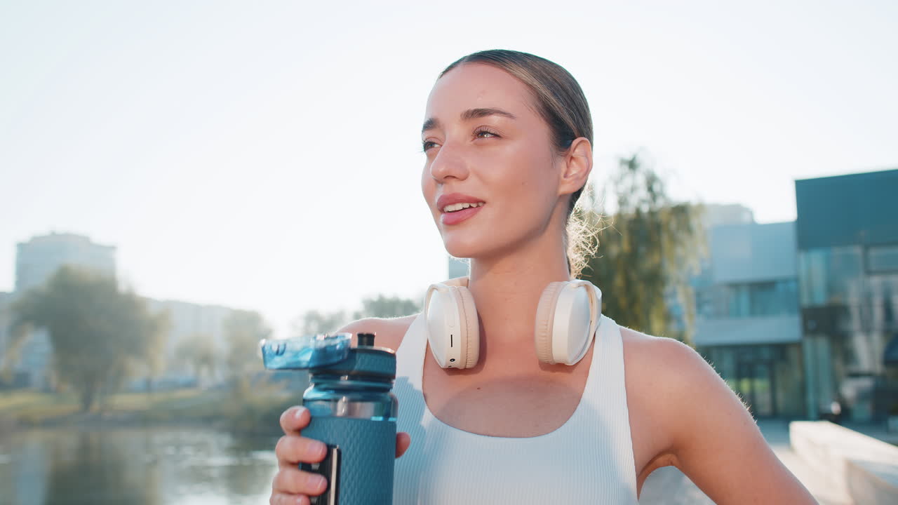 Atletica in forma corridore sportiva ragazza donna che beve acqua dalla bottiglia dopo l'esercizio di allenamento nel parco