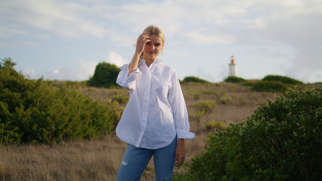 자신감 있는 모델이 홀로 언덕을 포즈를 취하고 있다. 소녀는 머리를 곧게 하고 미소 짓고 있다.