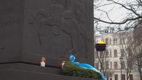 Candles-and-wreath-sit-on-stone-bas-relief-war-monument-in-Helsinki