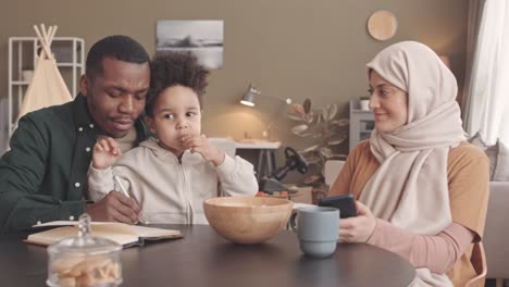 interracial muslim couple with child counting bills together at home