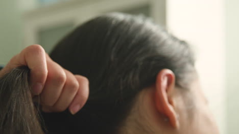 un primer plano extremo de una joven que desenreda su cabello con un cepillo, a cámara lenta